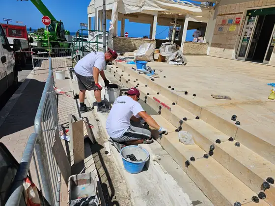 La squadra di Tower Edilizia al lavoro sui gradini esterni di un locale, con i livellanti fra le lastre